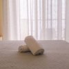 Letto matrimoniale con lenzuola grigie e due asciugamani bianchi arrotolati.