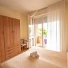 Una camera da letto con armadio in legno, letto matrimoniale e porta finestra aperta su un balcone.