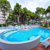 Piscina circondata da alberi e sedie a sdraio, con edifici sullo sfondo.