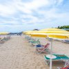 Spiaggia con file di ombrelloni gialli a righe e sedie a sdraio.