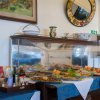 Buffet con piatti assortiti, bottiglie di condimenti e bicchieri su una tovaglia blu.