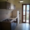 Cucina con piano cottura e frigo, porta-finestra sul fondo.