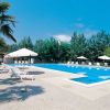 Piscina vuota con lettini bianchi e palme.