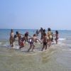 Bambini giocano in mare, formando un cerchio con gli adulti che li osservano.