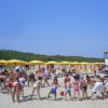 Bambini che giocano sulla spiaggia sotto ombrelloni gialli.