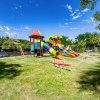 Parco giochi colorato con scivoli e altalene su un prato.
