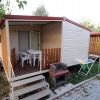 Una casetta mobile con veranda, tavolo, sedie e piccolo barbecue.