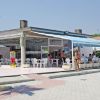 Ristorante all'aperto con sedie bianche e tettoia a strisce blu.