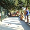 Persone osservano una partita di bocce su un campo all'aperto.